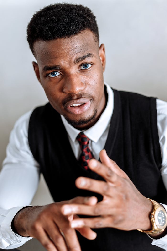 Portrait of an African American man in formal attire gesturing with confidence indoors.